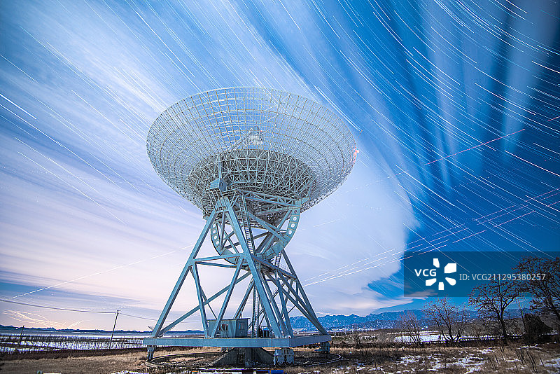 夜间射电望远镜在星空和云的流动下静静矗立在大地上图片素材