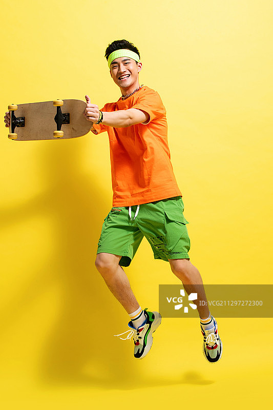 举着滑板跳跃的活力青年男人图片素材