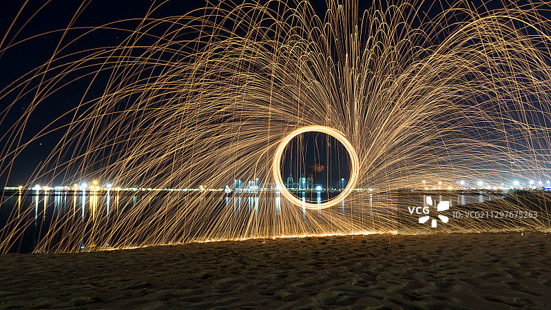 澳大利亚亚拉维尔，一名男子在夜空下的海滩上纺丝图片素材