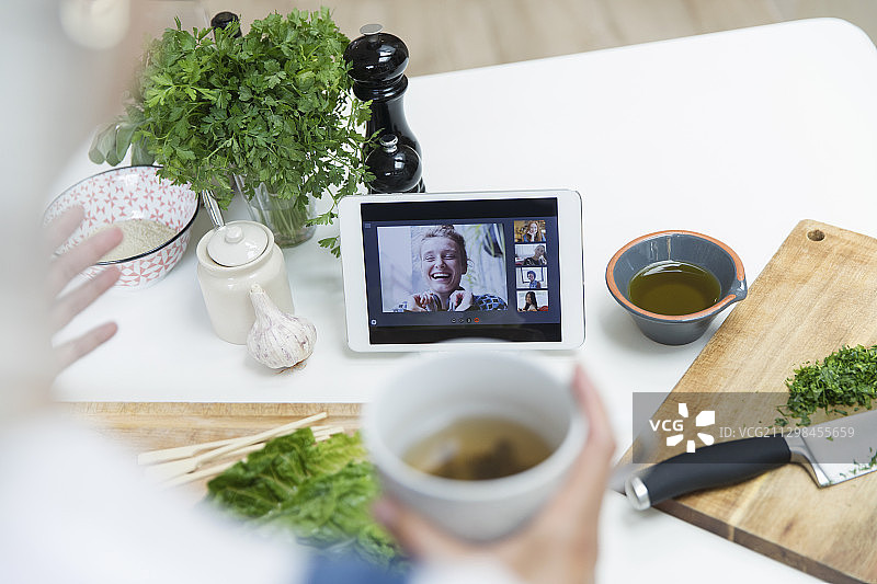 女人一边喝茶一边做饭一边和朋友视频聊天图片素材