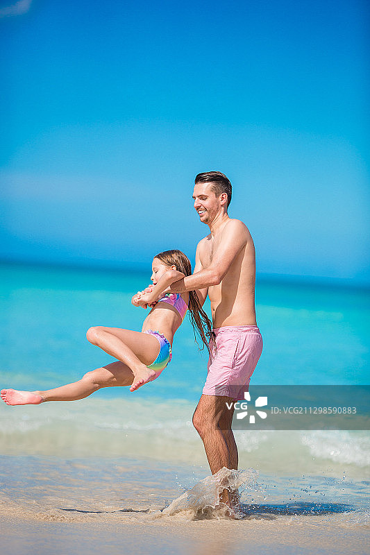 爸爸和女儿在沙滩上对着天空玩耍图片素材