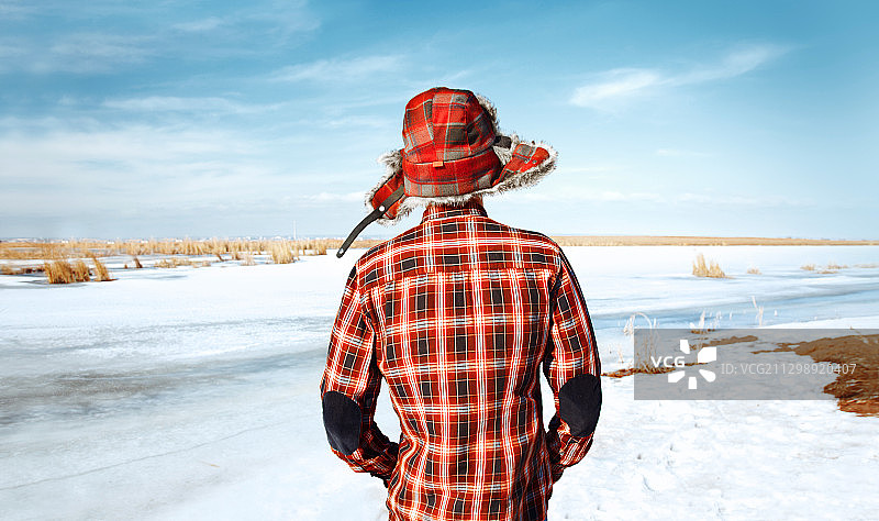 戴着红色捕兽帽和格子衬衫的男子在冬天的风景图片素材