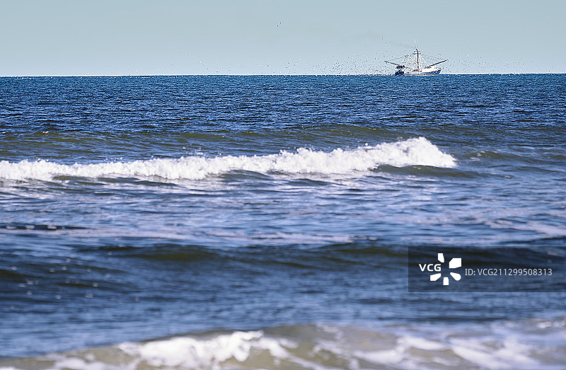 一艘在海上漂浮的渔船。海鸥在四周盘旋图片素材