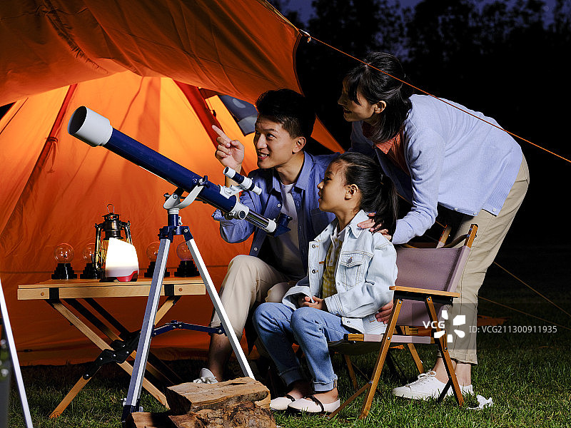 快乐的三口之家在户外使用天文望远镜图片素材