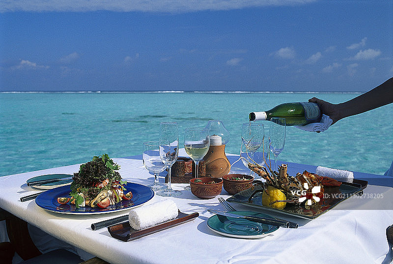 一张桌子躺在海滨阳光下，四季度假村，库达胡拉，马尔代夫，印度洋图片素材