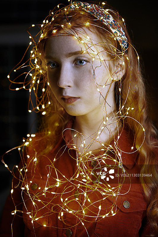 红发少女用圣诞彩灯装饰图片素材