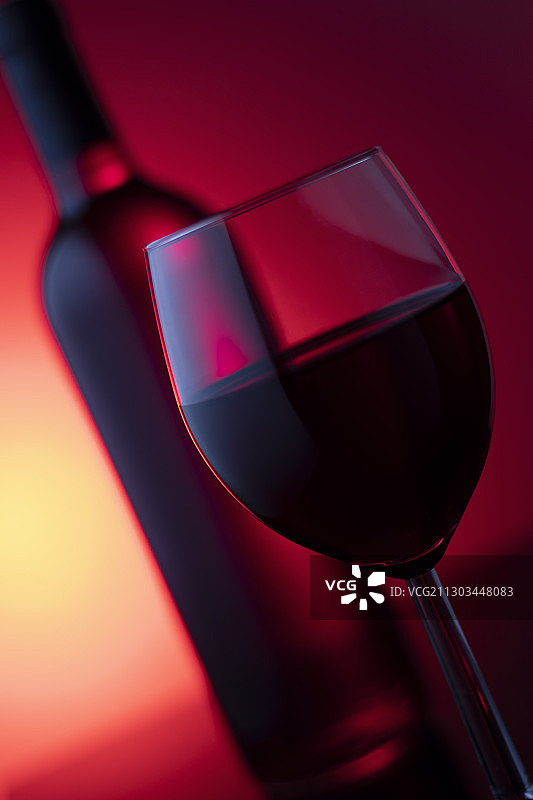 红色背景下的玻璃杯中的红酒特写图片素材