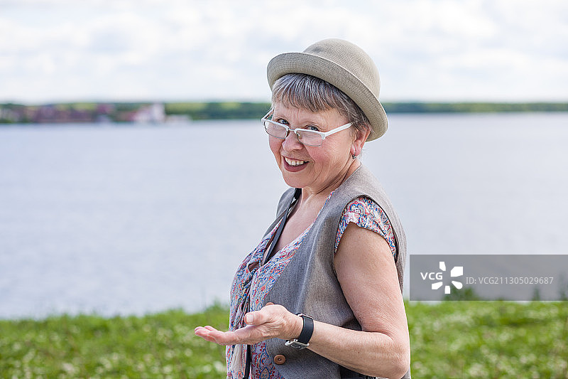 一个快乐的老妇人在湖边的肖像图片素材