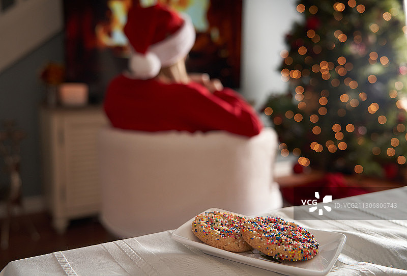 桌上放着糖饼干，圣诞老人坐在旁边图片素材