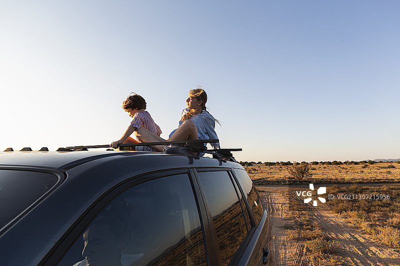 一个十几岁的女孩和她的弟弟在沙漠路上的一辆SUV上图片素材