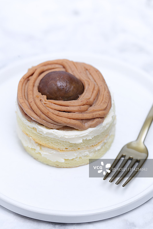 一个放在白色大理石背景上的栗子奶油蛋糕图片素材