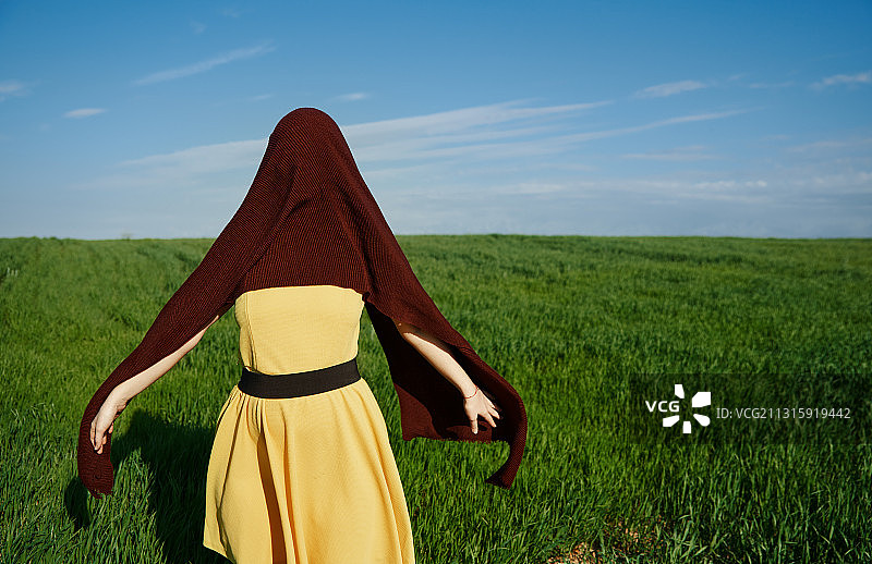 女人用织物遮盖着站在草原上图片素材