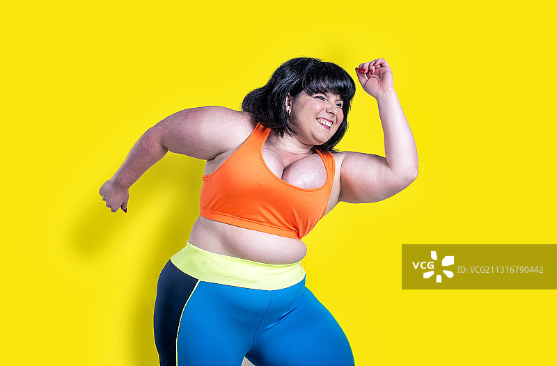 微笑的女人在黄色的背景下锻炼图片素材