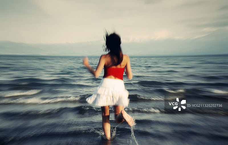模糊的女人向海边跑去的照片图片素材