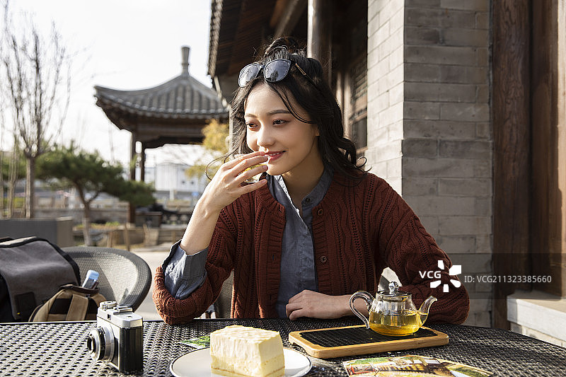 青年女子城市旅行在户外咖啡馆喝茶吃甜品休息图片素材