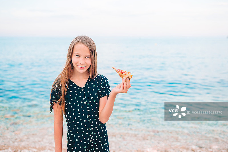微笑的女孩在海滩吃食物的肖像天空图片素材