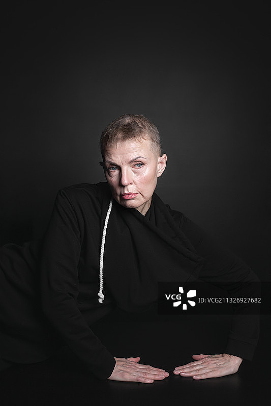 俄罗斯，一个成熟的女人，剪短的头发透过白色背景上的一条狭缝窥视图片素材