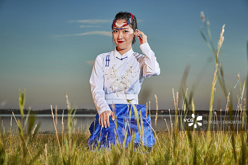 草原上穿着蒙古族传统服饰的亚洲年轻女性图片素材