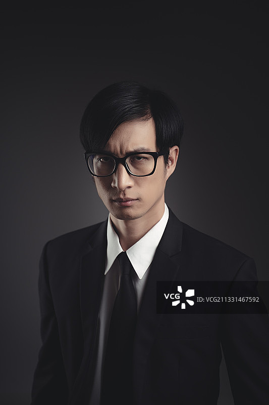 年轻商人的肖像戴着眼镜在黑色的背景图片素材