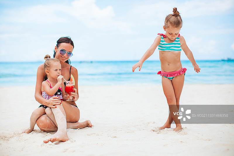 可爱的小女孩和妈妈在热带白色沙滩上图片素材