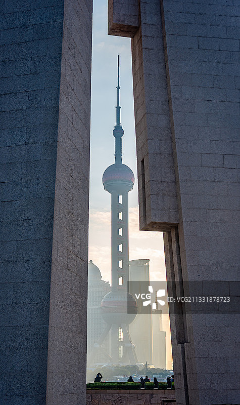透过上海人民英雄纪念塔的建筑结构看到日出时分的东方明珠塔图片素材