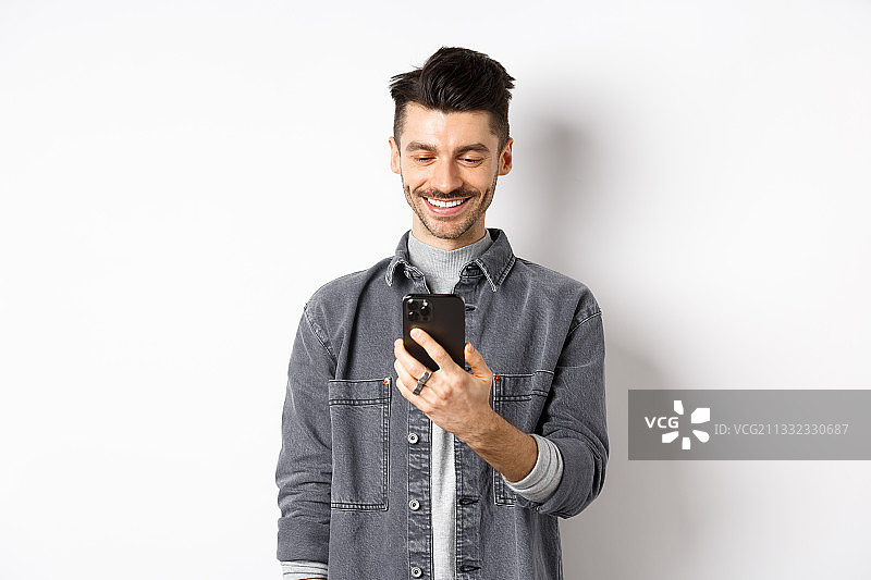 在白色背景下使用手机的微笑男子的肖像图片素材