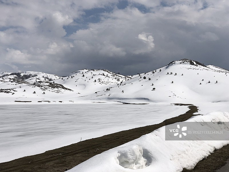 白雪皑皑的山峰映衬着黑山的天空图片素材