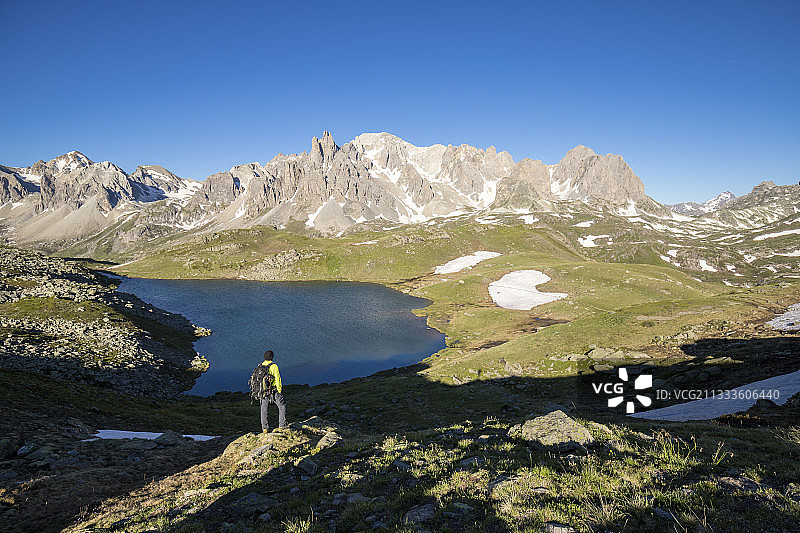 Vallee de La Claree，法国上阿尔卑斯奈瓦什，徒步旅行者凝视着长湖(2387米)，背景是赛赛山脉(3093米)图片素材