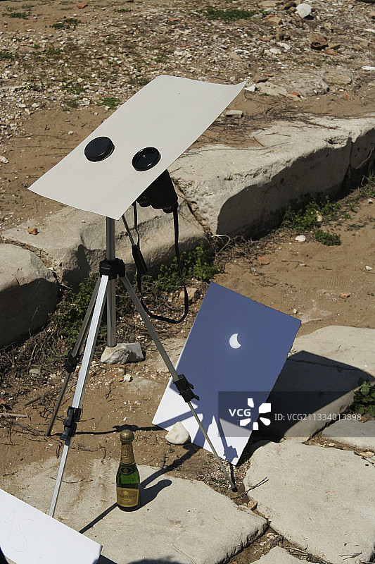 一副双筒望远镜将太阳图像投射到白色屏幕上。图片素材