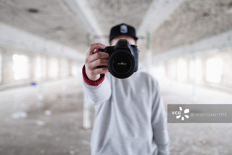 美国密歇根州底特律市，一名年轻人举着相机站在废弃的建筑中图片素材