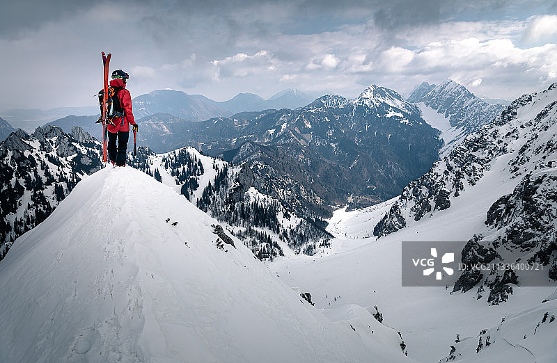 一个人站在白雪覆盖的山上，背靠天空图片素材