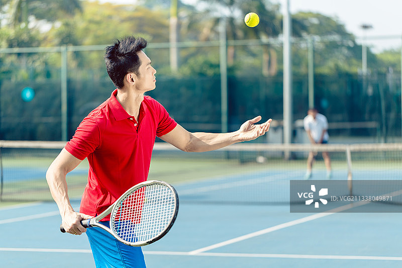 中国职业网球运动员在一场困难的比赛开始时，在发球后准备用球拍击球图片素材