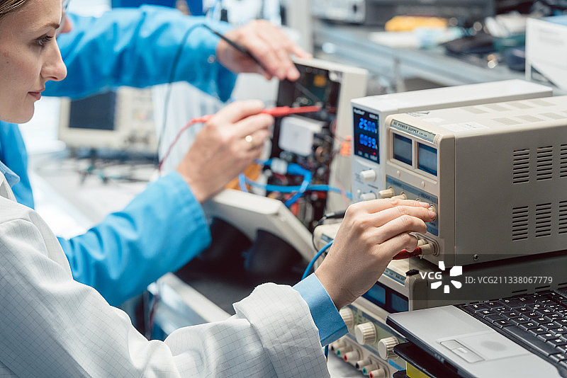 两名电子工程师在实验室测试台上测量新产品的EMC兼容性图片素材