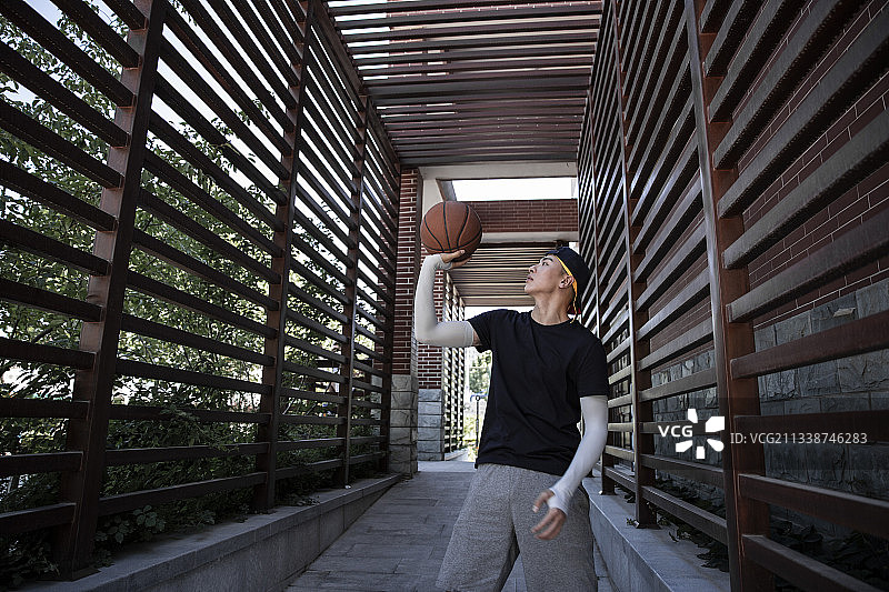 一个打篮球青年男子在学校走廊嬉戏练习投篮图片素材