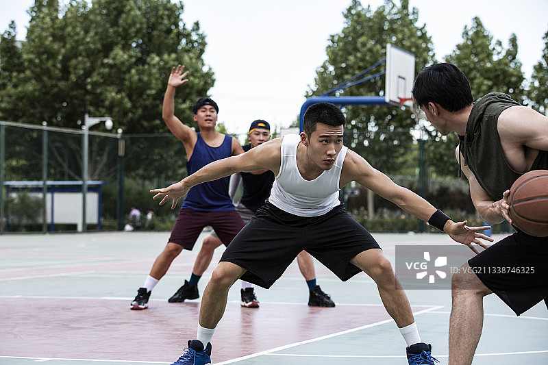四个青年男子在学校篮球场打篮球比赛图片素材