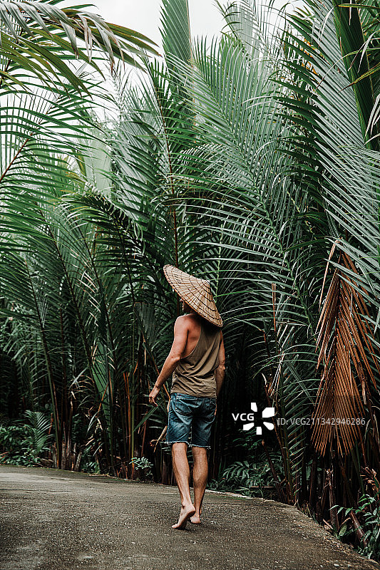 一个男人在热带的小路上，戴着帽子，穿着t恤图片素材