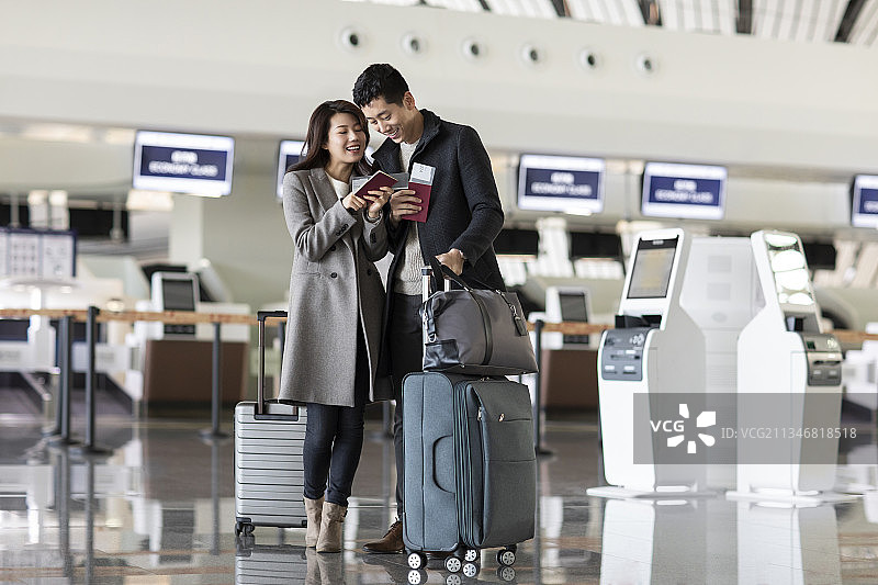 快乐的年轻夫妇在机场拿着机票和护照图片素材