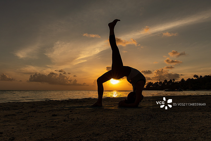 法国波利尼西亚，波拉波拉，女人在日落时在海滩上锻炼的剪影图片素材