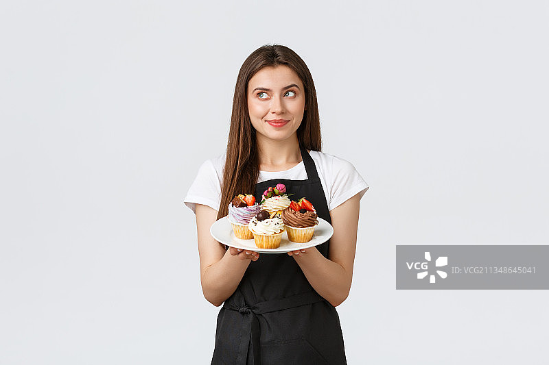 微笑的年轻女子手拿蛋糕，站在白色背景下图片素材