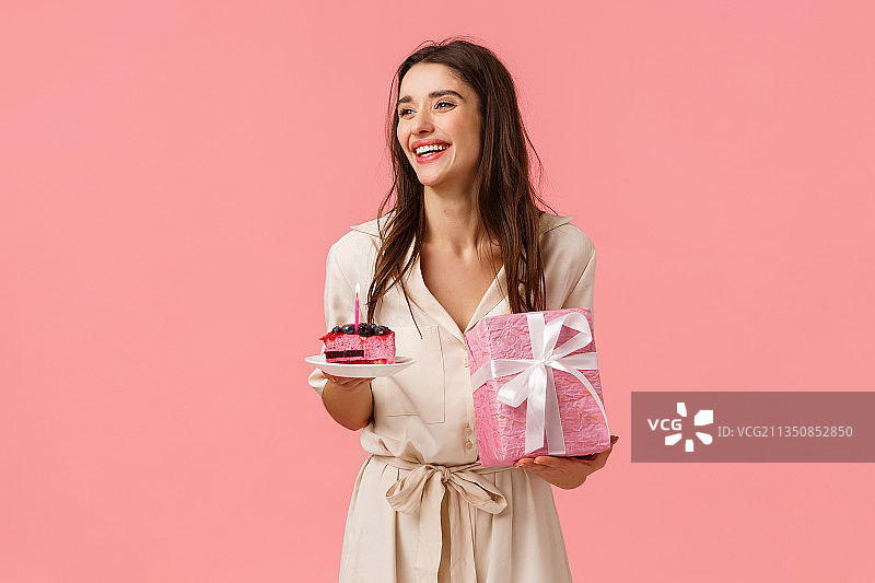 微笑的女人拿着礼品盒在粉红色的背景下图片素材