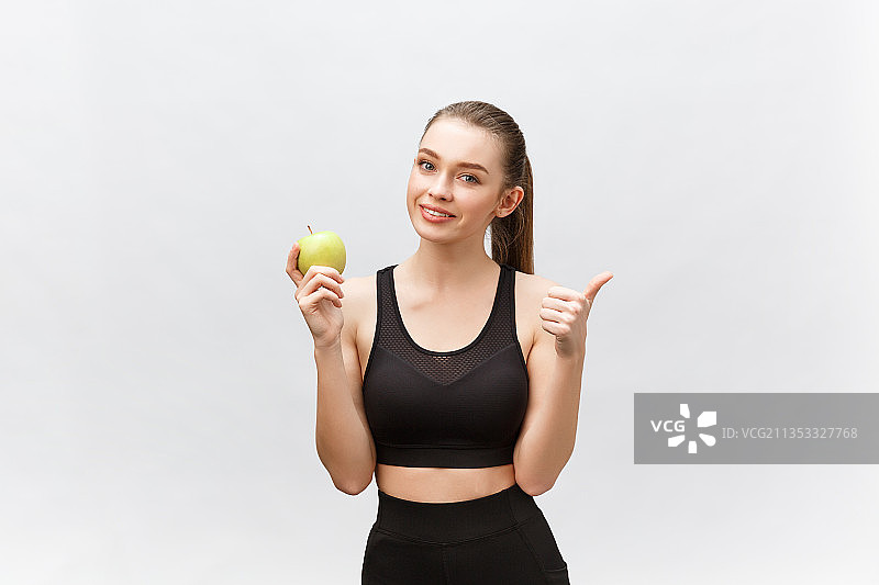 年轻女子手持苹果站在白色背景下的肖像图片素材