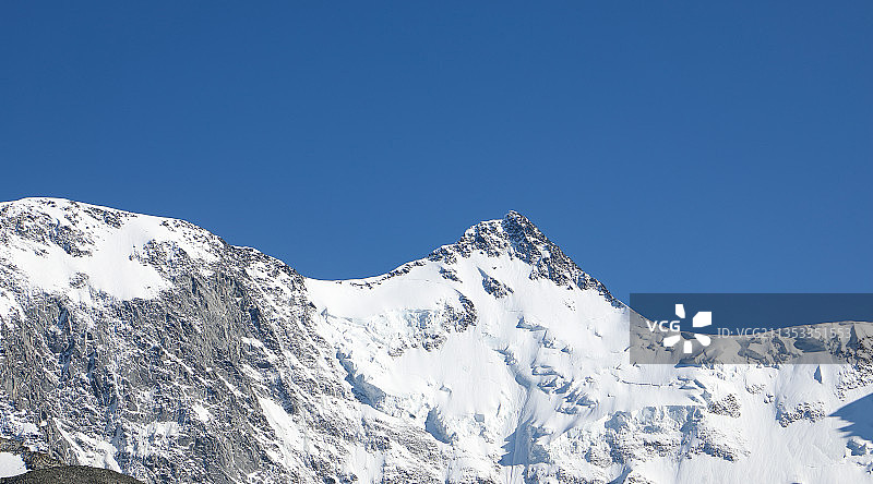 低角度的观点，雪山顶晴朗的蓝天图片素材