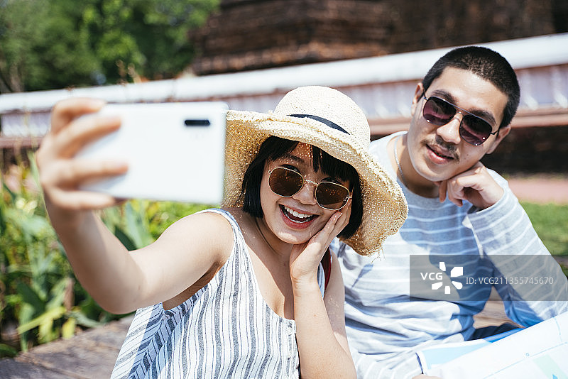 亚洲泰国夫妇戴着太阳镜用智能手机自拍。图片素材