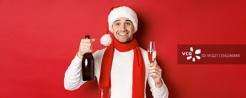 戴着圣诞老人帽子的微笑男人的肖像，站在红色的背景下图片素材