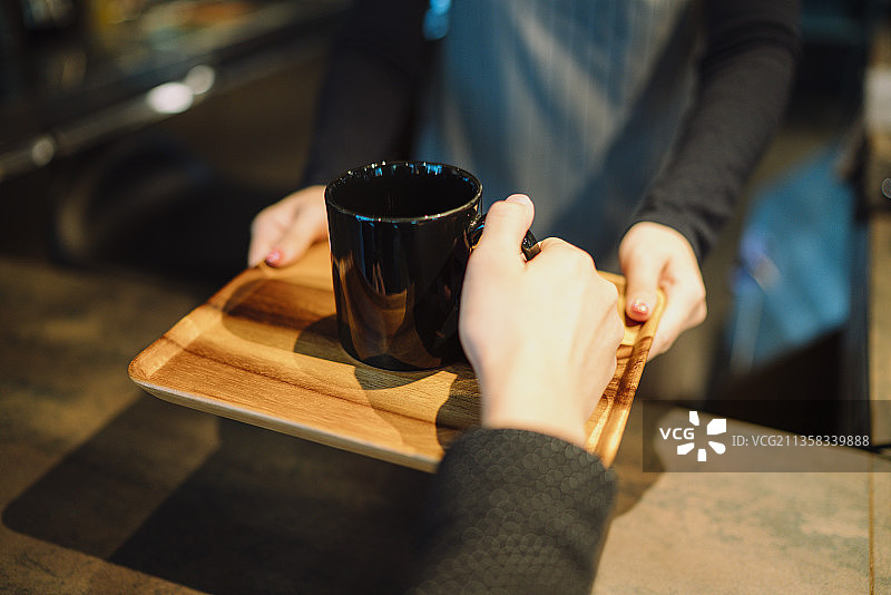 顾客从咖啡师手中接过热咖啡的特写镜头。图片素材