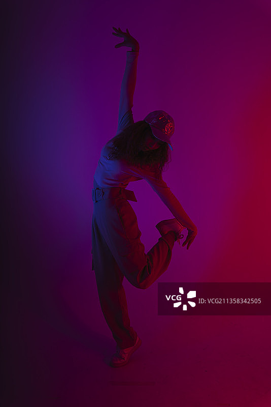 年轻的嬉皮女人的肖像在黑暗的霓虹灯背景下跳舞。图片素材