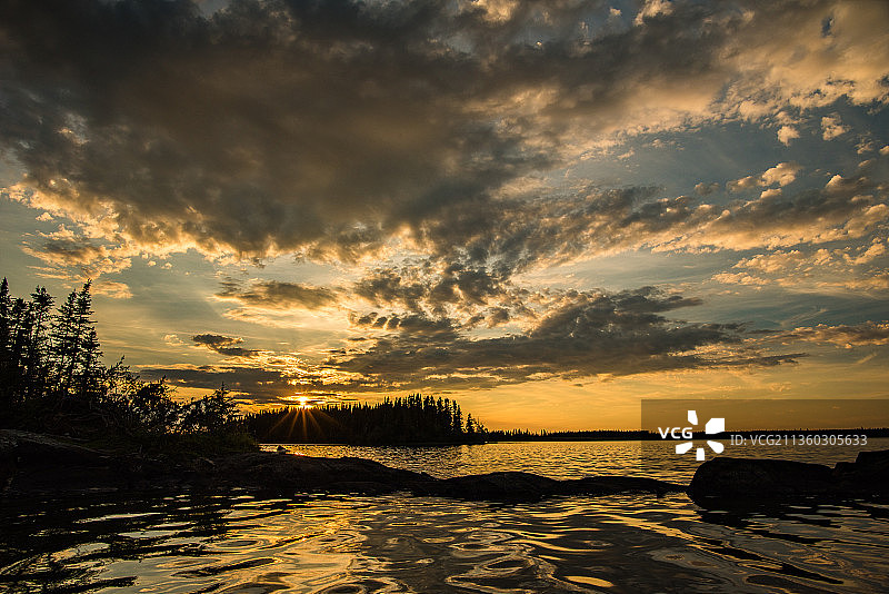 在湖上，日落时大海映衬着戏剧性的天空图片素材