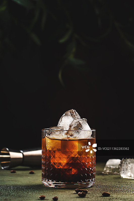 黑俄罗斯鸡尾酒，特写的威士忌杯子在桌子上对黑色的背景图片素材