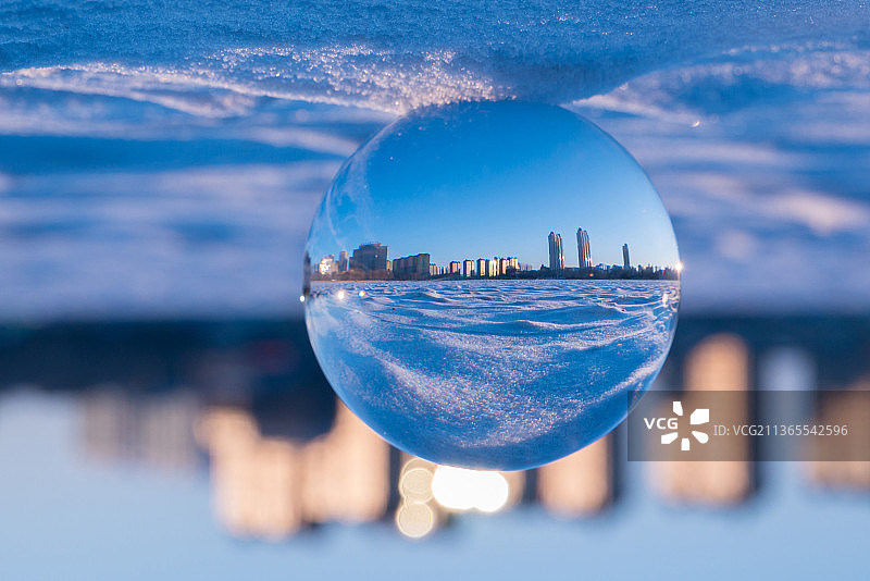 冬天冰面上的水晶球，城市天际线，蓝色星球图片素材