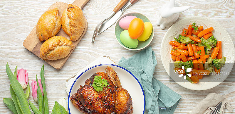 白色质朴的餐桌上摆放着复活节食物彩色鸡蛋，烤鸡图片素材